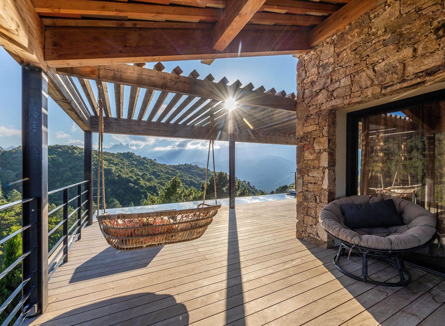 Balançoires et fauteuils face à la piscine à débordement - Villa Nature - Espaces extérieurs